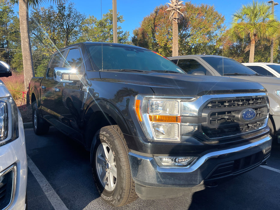 Black Ford truck parked in a lot with trees in the background with chrome accessories