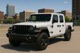 White Jeep gladiator parked in an urban setting with buildings abs6807blk