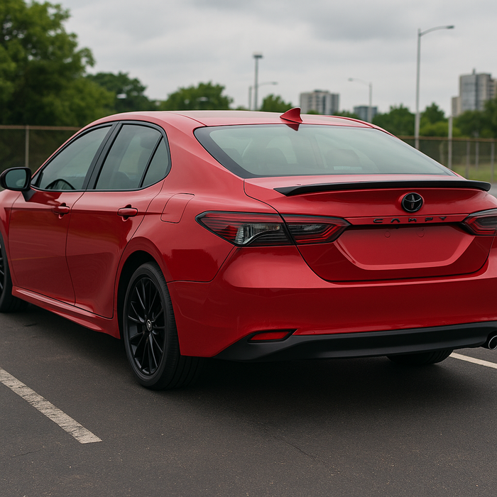 Red car parked on a road with a cloudy sky in the background and gloss black spoiler