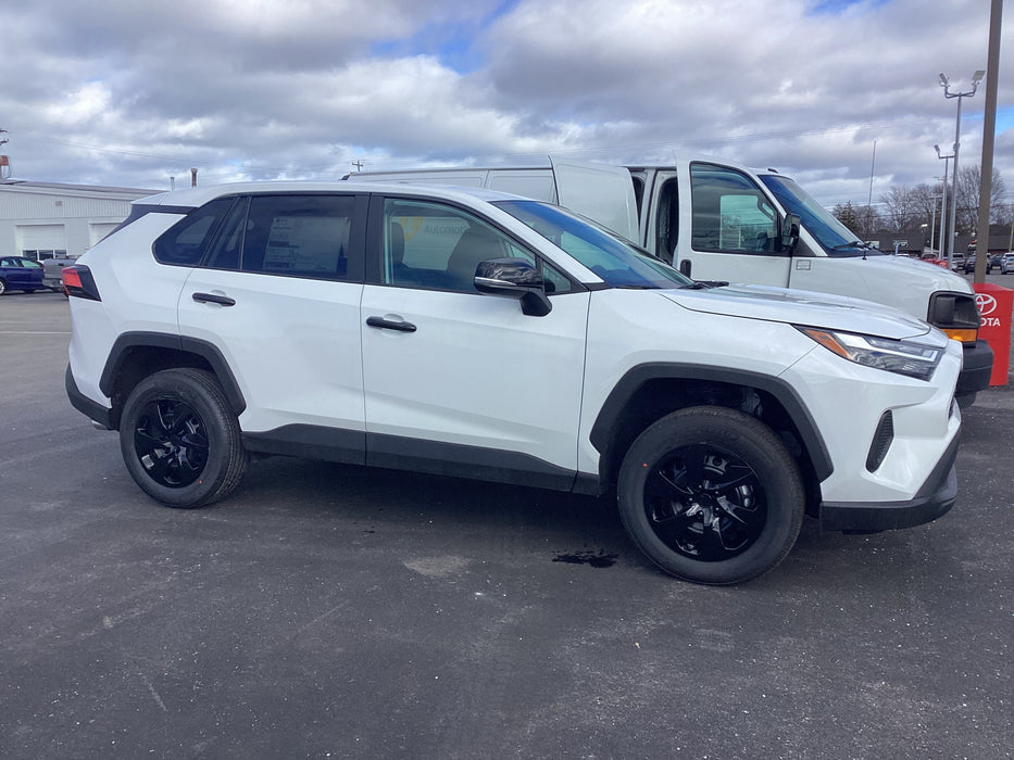 White SUV with black hubcaps parked in a lot with a cloudy sky.