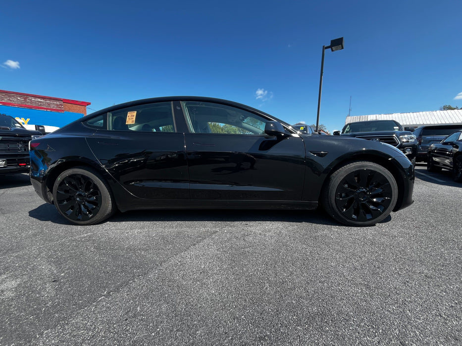 Black car parked in a lot with black hubcaps installed