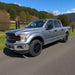 Silver Ford truck on a road with chrome delete trim installed