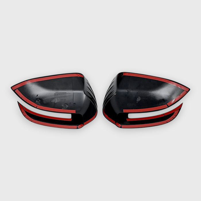 Black car mirror covers with white trim on a light gray background